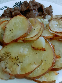Una foto de Trozos de carne con rodajas de papas al horno