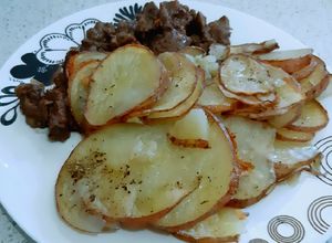 Una foto de Trozos de carne con rodajas de papas al horno