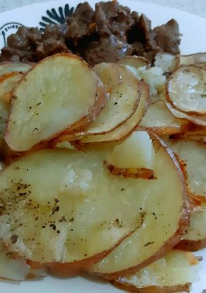 Una foto de Trozos de carne con rodajas de papas al horno