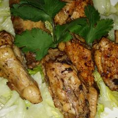 A picture of Yummy chicken wings and drums on salad.