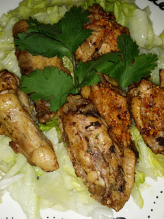A picture of Yummy chicken wings and drums on salad.