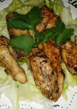 A picture of Yummy chicken wings and drums on salad.