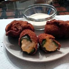 A picture of stuffed jalapenos wrapped in bacon.