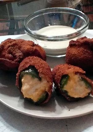 A picture of stuffed jalapenos wrapped in bacon.