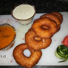 A picture of Medu vada with sambhar and coconut chutney.