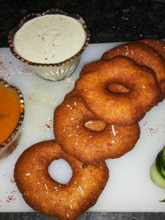 A picture of Medu vada with sambhar and coconut chutney.