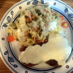 A picture of chicken fried steak with gravy and egg noodles.