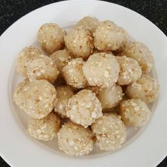 A picture of Semolina balls coated with peanuts and sugar.
