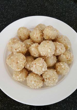 A picture of Semolina balls coated with peanuts and sugar.