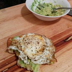 A picture of toasted ciabatta slice with mashed avocado spread and fried egg.