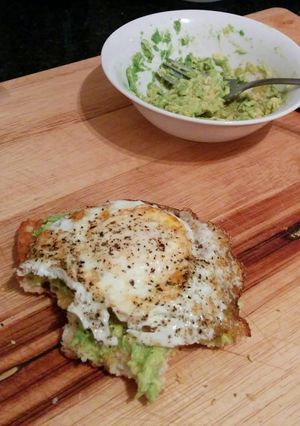 A picture of toasted ciabatta slice with mashed avocado spread and fried egg.