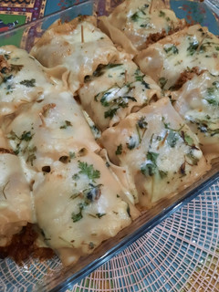 A picture of Tikka Lasagna roll ups with cheese sauce.