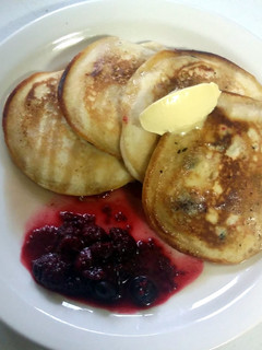 A picture of Fluffy pancakes with maple syrup butter and seasonal berries.