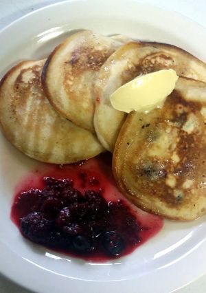 A picture of Fluffy pancakes with maple syrup butter and seasonal berries.