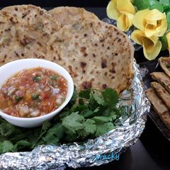 A picture of Stuffed paneer paratha with tomato onion chutney.