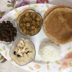 A picture of Puri, sooji halwa, white and black chana with rice.