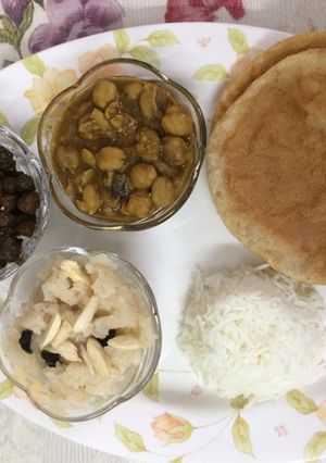 A picture of Puri, sooji halwa, white and black chana with rice.
