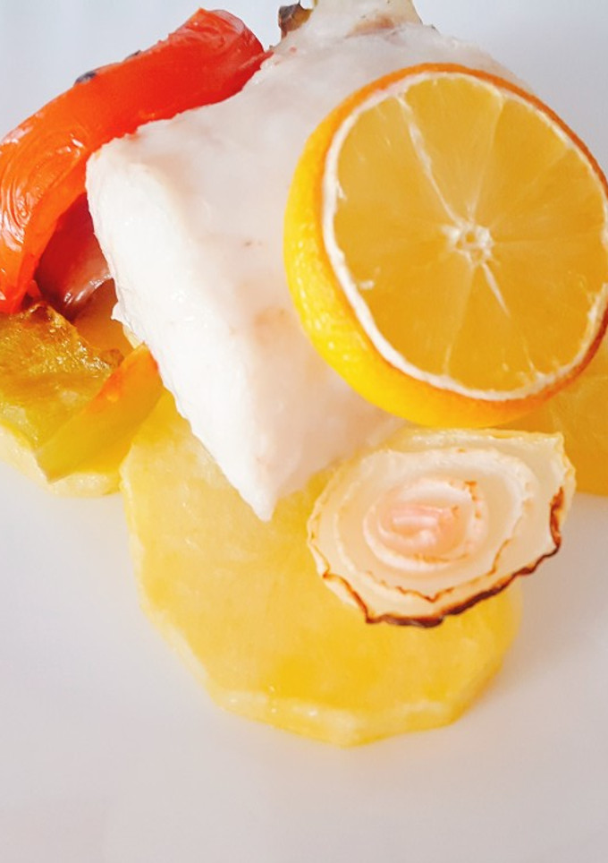 Una foto de Merluza con limón en cama de verduras al horno