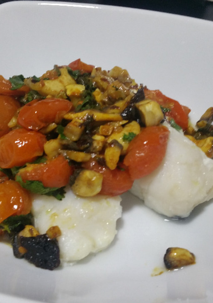 Una foto de Merluza con tomates y otras cosas