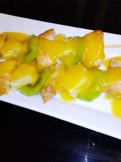 Una foto de Brochetas de pollo, piña y kiwi, con salsa de naranja