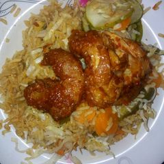 A picture of Jallof rice with cucumber and peper meat.