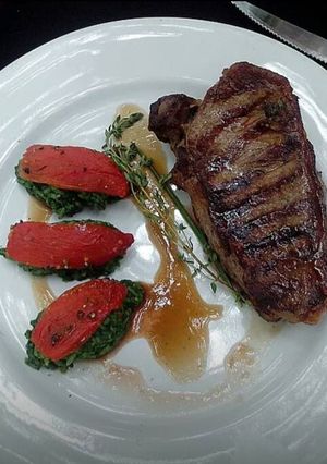 Una foto de Bife de chorizo con arroz verde y tomates laqueados