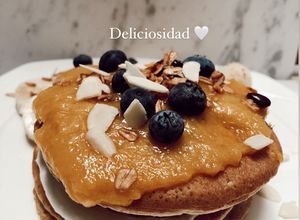 Una foto de Pancakes 🥞 de harina de almendra y coco, salsa de mango 🥭 en sartén, arándanos y yogurt de vainilla🤤