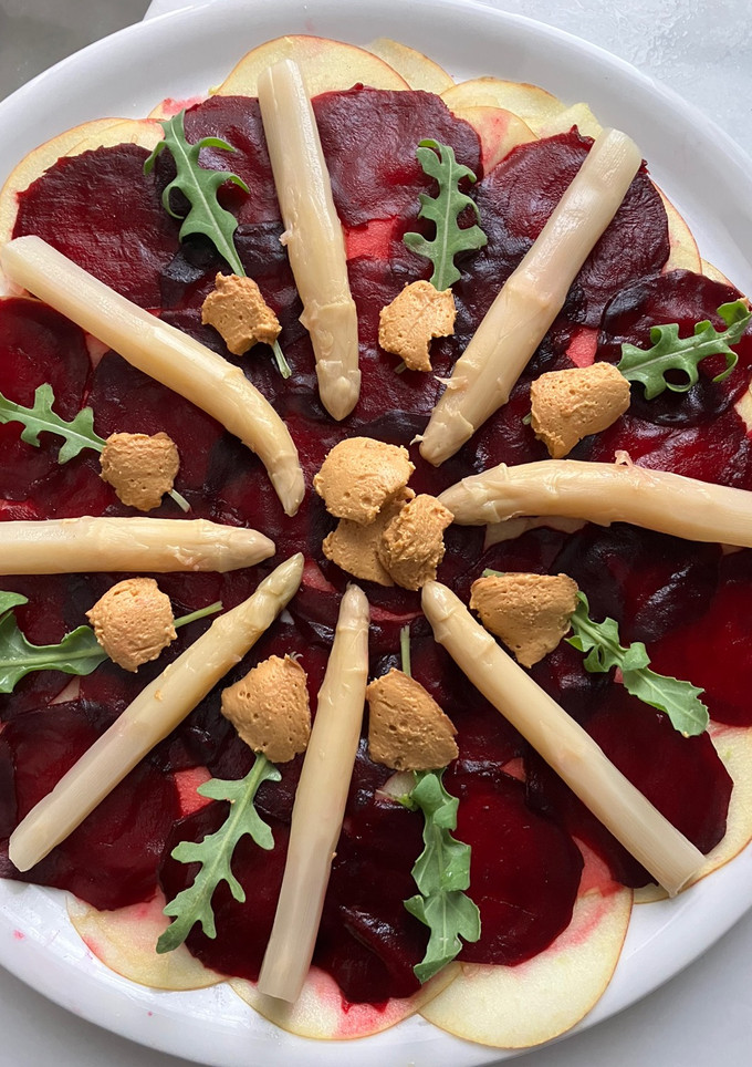 Una foto de Ensalada de espárragos blancos sobre carpaccio de manzana y remolacha