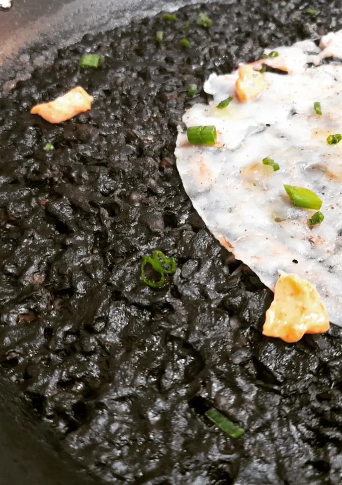 Una foto de Arroz negro v2 con carpaccio de gambas