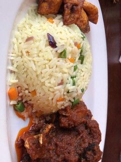 A picture of Fried rice and goat meat sauce and fried plantain.