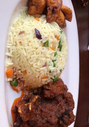 A picture of Fried rice and goat meat sauce and fried plantain.