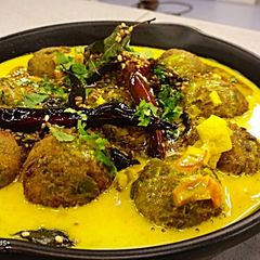 A picture of Mattar kofte stuffed with apricot in coconut gravy.