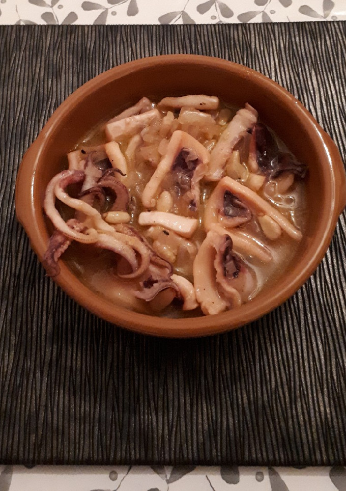 Una foto de Tapa de calamares con cebolla, piñones y vino blanco