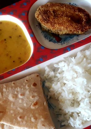 A picture of Dal, rice, with fish fry and roti.