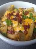 Papas rostizadas con queso cheddar, tocineta y cebollín
