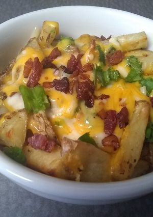 Una foto de Papas rostizadas con queso cheddar, tocineta y cebollín