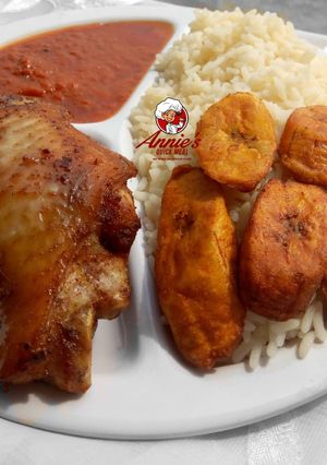 A picture of Boiled rice,fried plantain,fried turkey and tomato sauce.