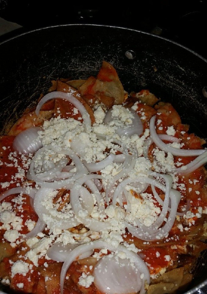 Una foto de Chilaquiles rojos con cebolla y queso