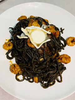 Una foto de Espaguetis negros con gambas y queso de cabra