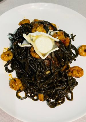 Una foto de Espaguetis negros con gambas y queso de cabra