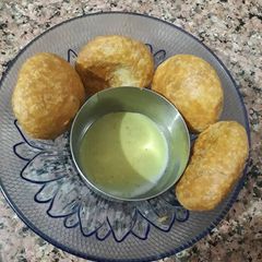 A picture of Masala moong dal kachori with green chutney.