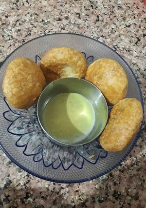 A picture of Masala moong dal kachori with green chutney.