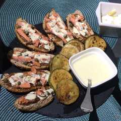 A picture of Tabla de tapas de salmón y alcaparras, zapallos italianos asados y salsa alioli.