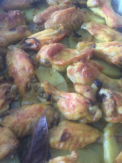 Una foto de Alitas y muslitos de pollo rustídas con patatas a la panadera al horno
