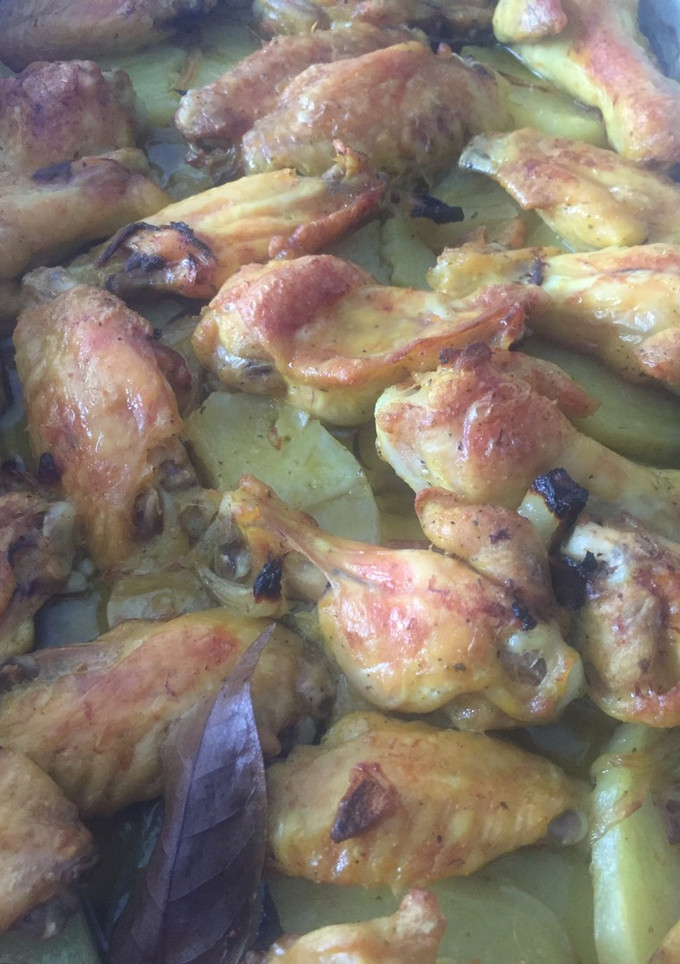 Una foto de Alitas y muslitos de pollo rustídas con patatas a la panadera al horno
