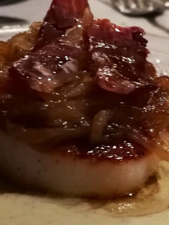 Una foto de Vieira sobre parmentier de alcachofa, con cebolla caramelizada y crujiente de ibérico