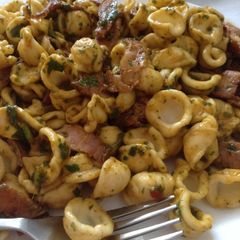 A picture of Conchiglie pasta with smoked ham bits in cilantro paprika dressing.