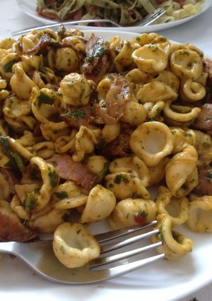 A picture of Conchiglie pasta with smoked ham bits in cilantro paprika dressing.