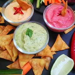 A picture of Nachos with 3 different hummus dips.