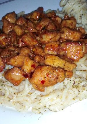 A picture of White sauce pasta with schezwan chicken.